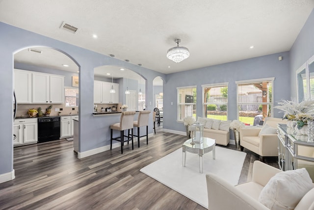 living room with dark wood finished floors, baseboards, recessed lighting, a textured ceiling, and arched walkways