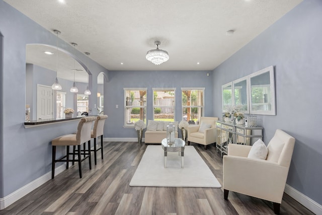 living area featuring wood finished floors, baseboards, recessed lighting, and arched walkways