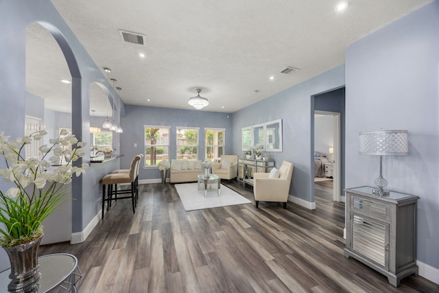 living area with baseboards, wood finished floors, a textured ceiling, arched walkways, and recessed lighting