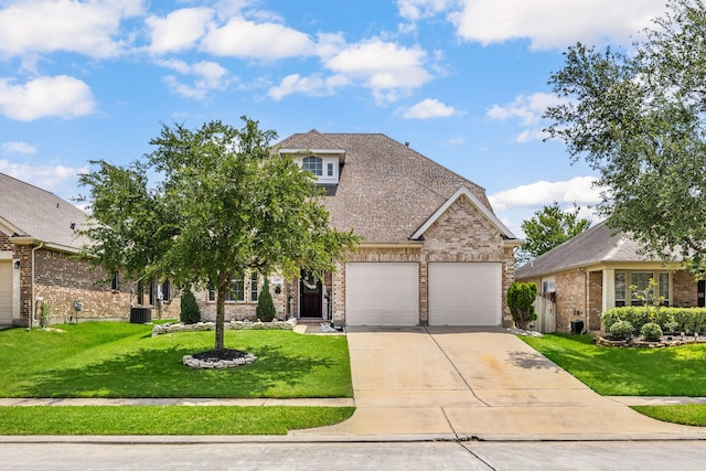view of front of property with brick siding, driveway, a front yard, central AC unit, and a garage