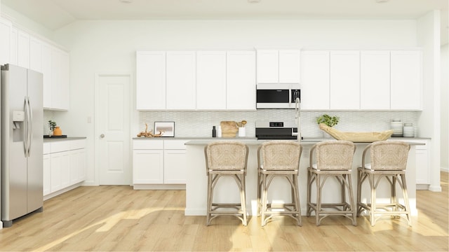 kitchen featuring refrigerator with ice dispenser, white microwave, stove, light wood-style flooring, and backsplash