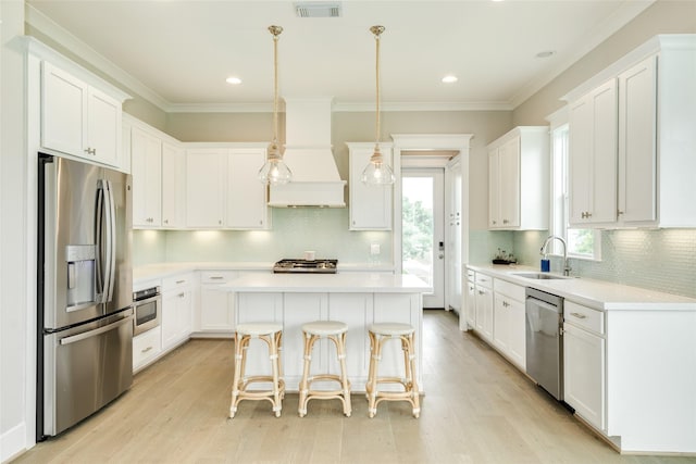 9 Caravelle Ct, Galveston, TX 77554 - kitchen with stainless steel appliances, a sink, a kitchen island, light countertops, and white cabinets