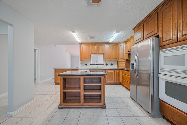 22010 Elsinore Dr, Katy, TX 77450 - kitchen with white appliances, a sink, light tile patterned flooring, a textured ceiling, and dark countertops
