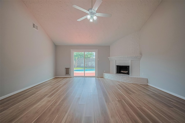 22010 Elsinore Dr, Katy, TX 77450 - unfurnished living room with a textured ceiling, lofted ceiling, ceiling fan, wood finished floors, and a fireplace
