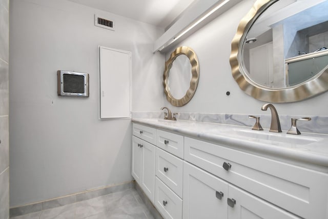 bathroom with double vanity, tile patterned flooring, and baseboards