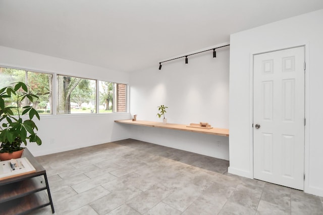 unfurnished office with light tile patterned floors and track lighting