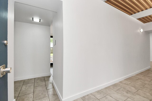 corridor featuring baseboards and light tile patterned flooring