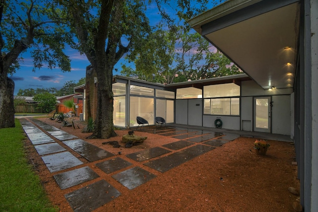 back of property at dusk featuring a patio