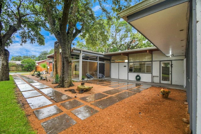 rear view of house with a patio area, a sunroom, and fence