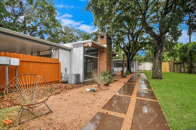 view of yard featuring a storage shed, cooling unit, an outbuilding, and a sunroom