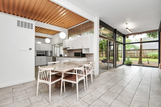 dining space with a wall of windows, light tile patterned flooring, and baseboards