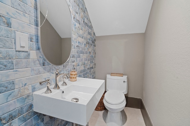 3835 Seabreeze Ln, Galveston, TX 77554 - bathroom with toilet, a sink, vaulted ceiling, and tile walls