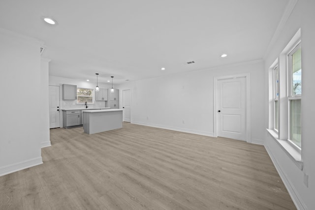 unfurnished living room with recessed lighting, ornamental molding, light wood-style floors, and baseboards