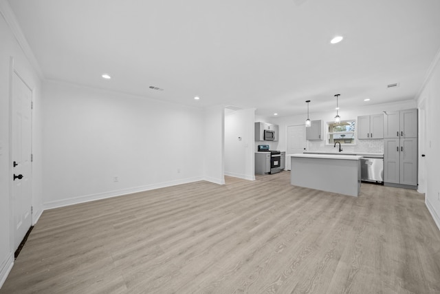 unfurnished living room featuring recessed lighting, light wood-style floors, ornamental molding, baseboards, and a sink