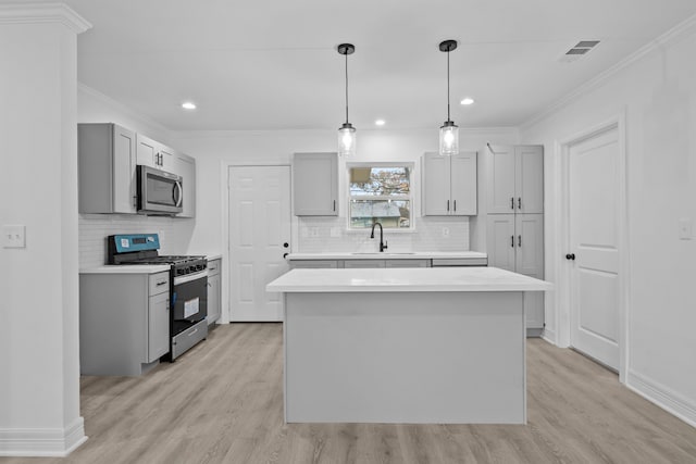 kitchen featuring appliances with stainless steel finishes, a sink, gray cabinetry, light wood finished floors, and crown molding
