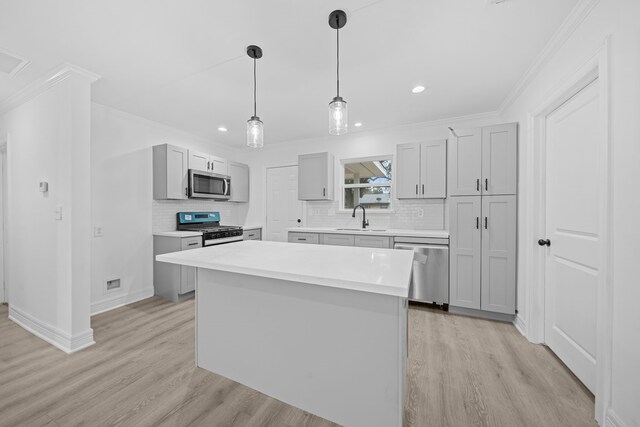 kitchen featuring appliances with stainless steel finishes, a sink, light wood-type flooring, tasteful backsplash, and crown molding
