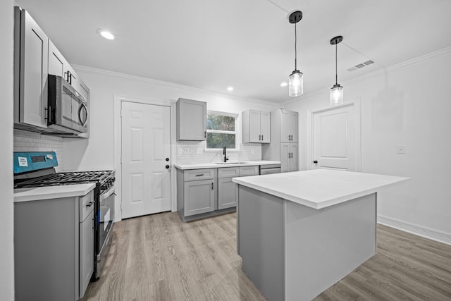 kitchen featuring gray cabinets, appliances with stainless steel finishes, a sink, ornamental molding, and light wood-type flooring