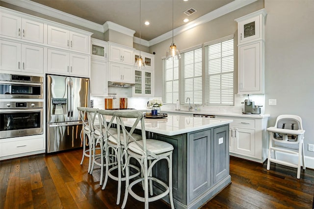 6003 Matthew Oaks Pl, Houston, TX 77007 - kitchen with stainless steel appliances, ornamental molding, dark wood finished floors, white cabinetry, and recessed lighting