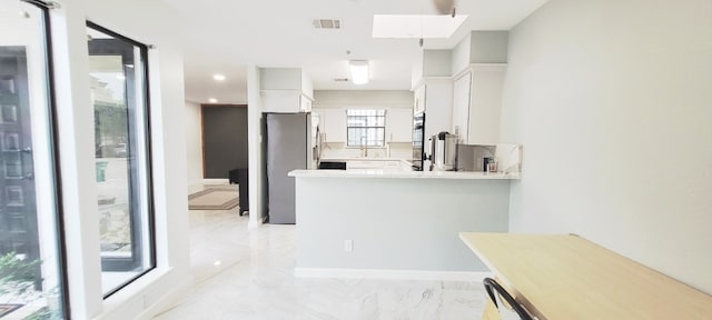 7515 Hopewell Ln, Houston, TX 77071 - kitchen with white cabinetry, a skylight, light countertops, light marble finish floors, and stainless steel fridge with ice dispenser