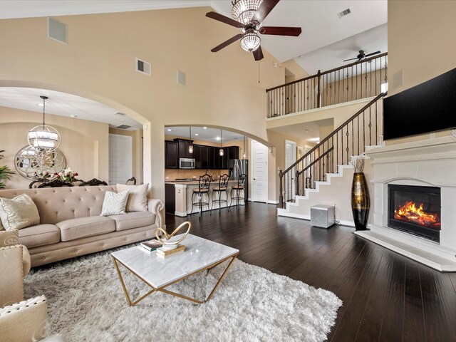 18118 Berry Garden Ln, Spring, TX 77379 - living area with a ceiling fan, dark wood-style flooring, arched walkways, high vaulted ceiling, and a glass covered fireplace