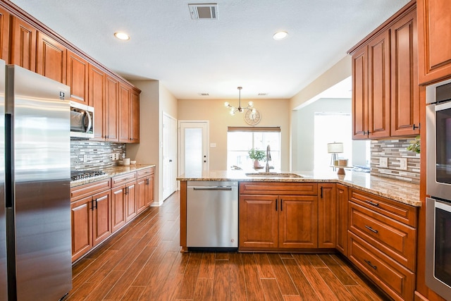 20815 Winlock Trace Dr, Katy, TX 77450 - kitchen with appliances with stainless steel finishes, a sink, a peninsula, dark wood-type flooring, and brown cabinetry