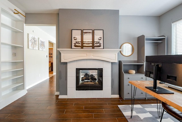 20815 Winlock Trace Dr, Katy, TX 77450 - home office featuring built in shelves, dark wood-type flooring, baseboards, and a tiled fireplace