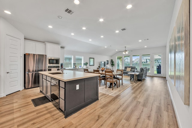 19015 Giara Pony Trl, Tomball, TX 77377 - kitchen with freestanding refrigerator, built in microwave, vaulted ceiling, light wood finished floors, and white cabinetry