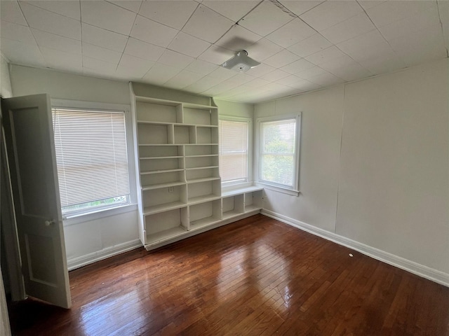 empty room with wood-type flooring, plenty of natural light, and baseboards