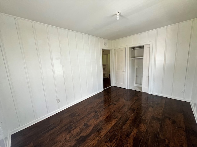 unfurnished bedroom featuring hardwood / wood-style floors, a decorative wall, and a closet