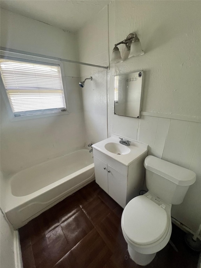 bathroom with toilet,  shower combination, vanity, a wainscoted wall, and wood finished floors