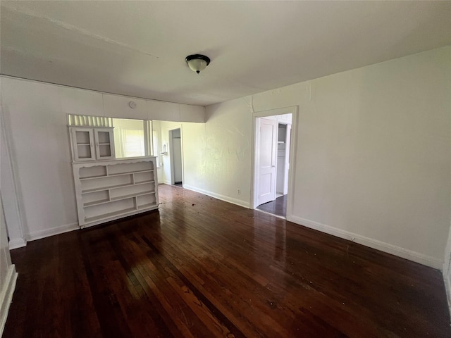 spare room with wood-type flooring and baseboards