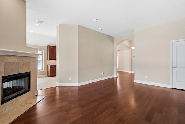 20506 Nellie Gail Trail Ln, Katy, TX 77450 - unfurnished living room featuring arched walkways, wood-type flooring, baseboards, a tile fireplace, and recessed lighting