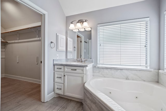 20506 Nellie Gail Trail Ln, Katy, TX 77450 - bathroom with vanity, a jetted tub, wood finished floors, a spacious closet, and vaulted ceiling
