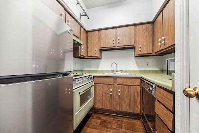 kitchen featuring freestanding refrigerator, gas stove, a sink, dishwasher, and dark wood finished floors