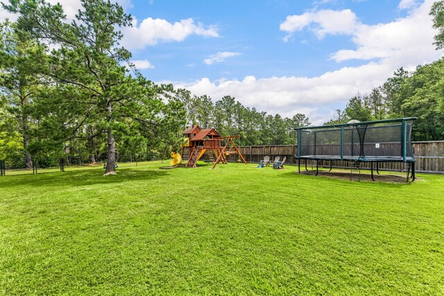 19509 Desna Dr, Porter, TX 77365 - view of yard featuring a trampoline, a playground, and view of wooded area