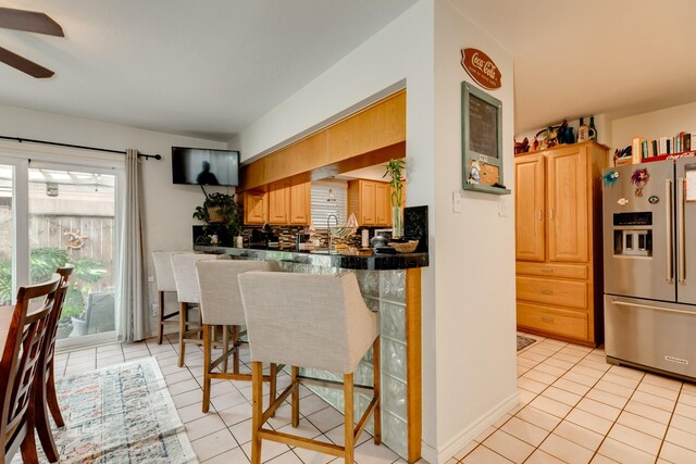 29 Quintana Dr, Galveston, TX 77554 - kitchen with stainless steel refrigerator with ice dispenser, dark countertops, a kitchen breakfast bar, light tile patterned floors, and a ceiling fan