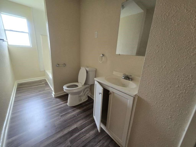 1300 Burbank St, Baytown, TX 77520 - bathroom with toilet, vanity, wood finished floors, shower / bath combination, and baseboards