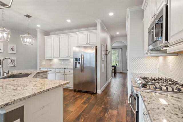 2023 Aspen Point Ln, Richmond, TX 77469 - kitchen with appliances with stainless steel finishes, a sink, crown molding, dark wood-type flooring, and arched walkways