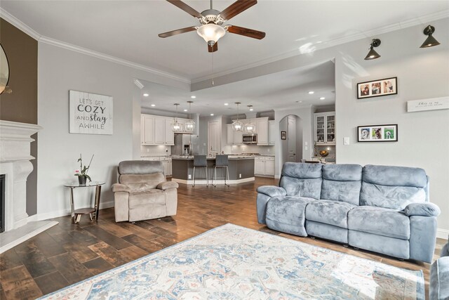2023 Aspen Point Ln, Richmond, TX 77469 - living area with ceiling fan, ornamental molding, a glass covered fireplace, dark wood finished floors, and arched walkways