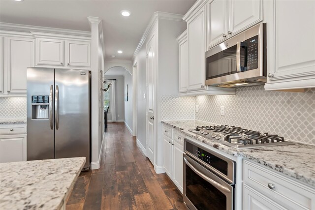 2023 Aspen Point Ln, Richmond, TX 77469 - kitchen featuring appliances with stainless steel finishes, arched walkways, dark wood-style flooring, white cabinets, and baseboards