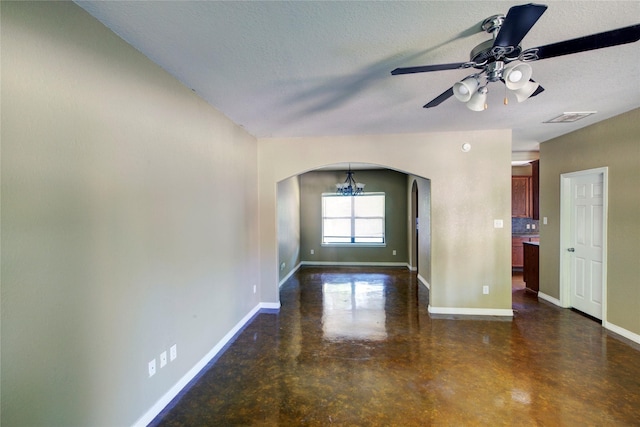 unfurnished room with arched walkways, concrete flooring, baseboards, ceiling fan, and a textured ceiling