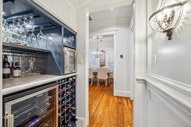 300 E 26th St, Houston, TX 77008 - indoor dry bar with ornamental molding, a chandelier, wine cooler, and light wood-type flooring