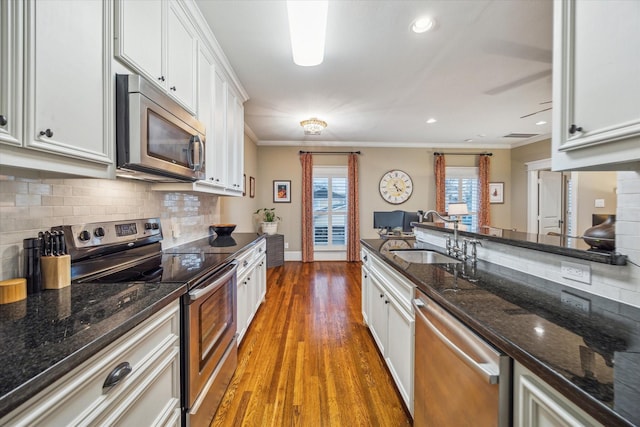 300 E 26th St, Houston, TX 77008 - kitchen featuring stainless steel appliances, a sink, ornamental molding, tasteful backsplash, and white cabinets