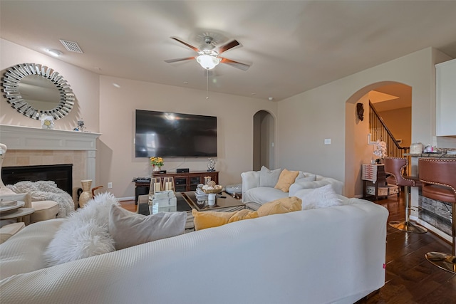 2812 Baywater Creek Ln, Pearland, TX 77089 - living room featuring arched walkways, a ceiling fan, dark wood-style flooring, a tile fireplace, and stairway