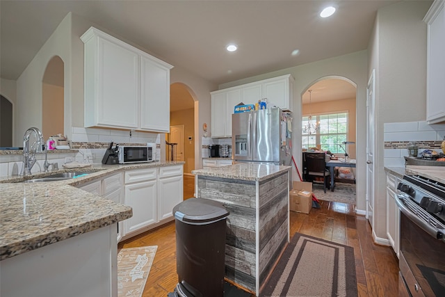 2812 Baywater Creek Ln, Pearland, TX 77089 - kitchen featuring stainless steel appliances, a sink, decorative backsplash, arched walkways, and light stone countertops