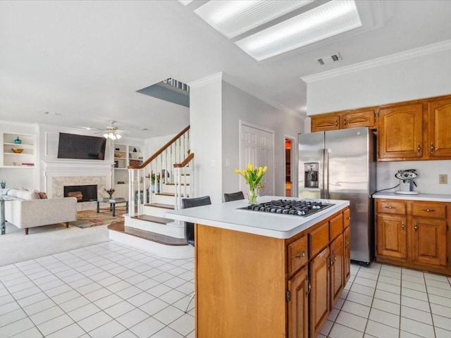 4614 Jamaica Dr, Sugar Land, TX 77479 - kitchen with stainless steel appliances, light tile patterned flooring, light countertops, a fireplace, and crown molding