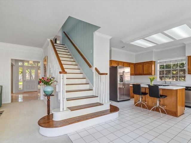 4614 Jamaica Dr, Sugar Land, TX 77479 - kitchen featuring stainless steel appliances, crown molding, brown cabinetry, light countertops, and a kitchen island