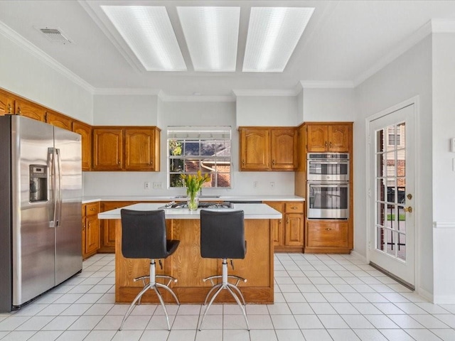 4614 Jamaica Dr, Sugar Land, TX 77479 - kitchen featuring appliances with stainless steel finishes, a center island, brown cabinets, light countertops, and ornamental molding
