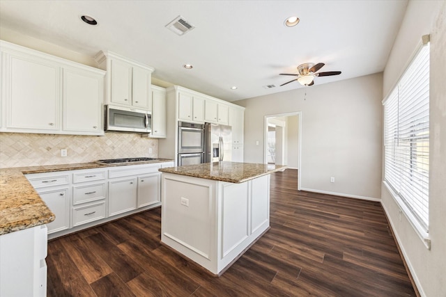 10906 Harvest Sun Dr, Houston, TX 77064 - kitchen featuring appliances with stainless steel finishes, ceiling fan, tasteful backsplash, dark wood-style flooring, and a kitchen island