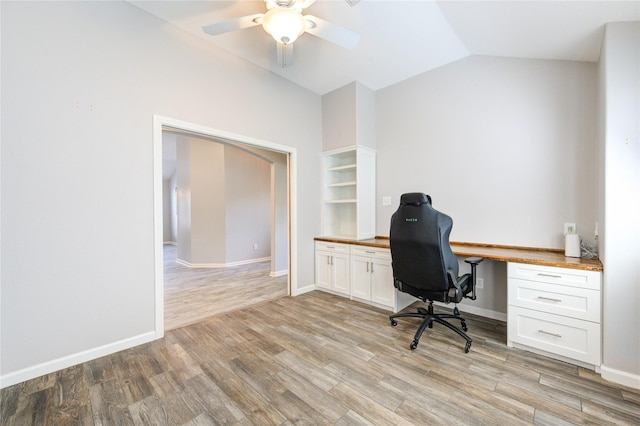 office area featuring light wood finished floors, ceiling fan, lofted ceiling, built in desk, and baseboards